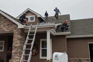 men putting Christmas Lights on house