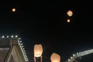 Christmas Lights on house with people releasing candle lanterns